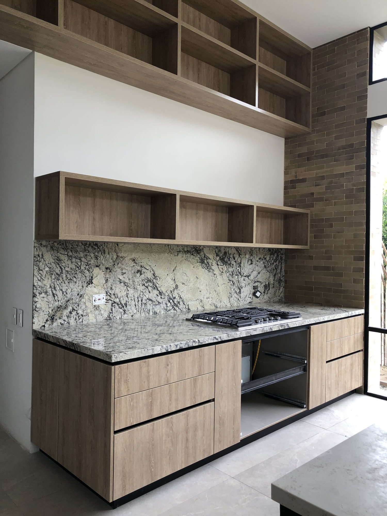 Cocina moderna con salpicadero en piedra, mobiliario en madera y zona de trabajo integrada