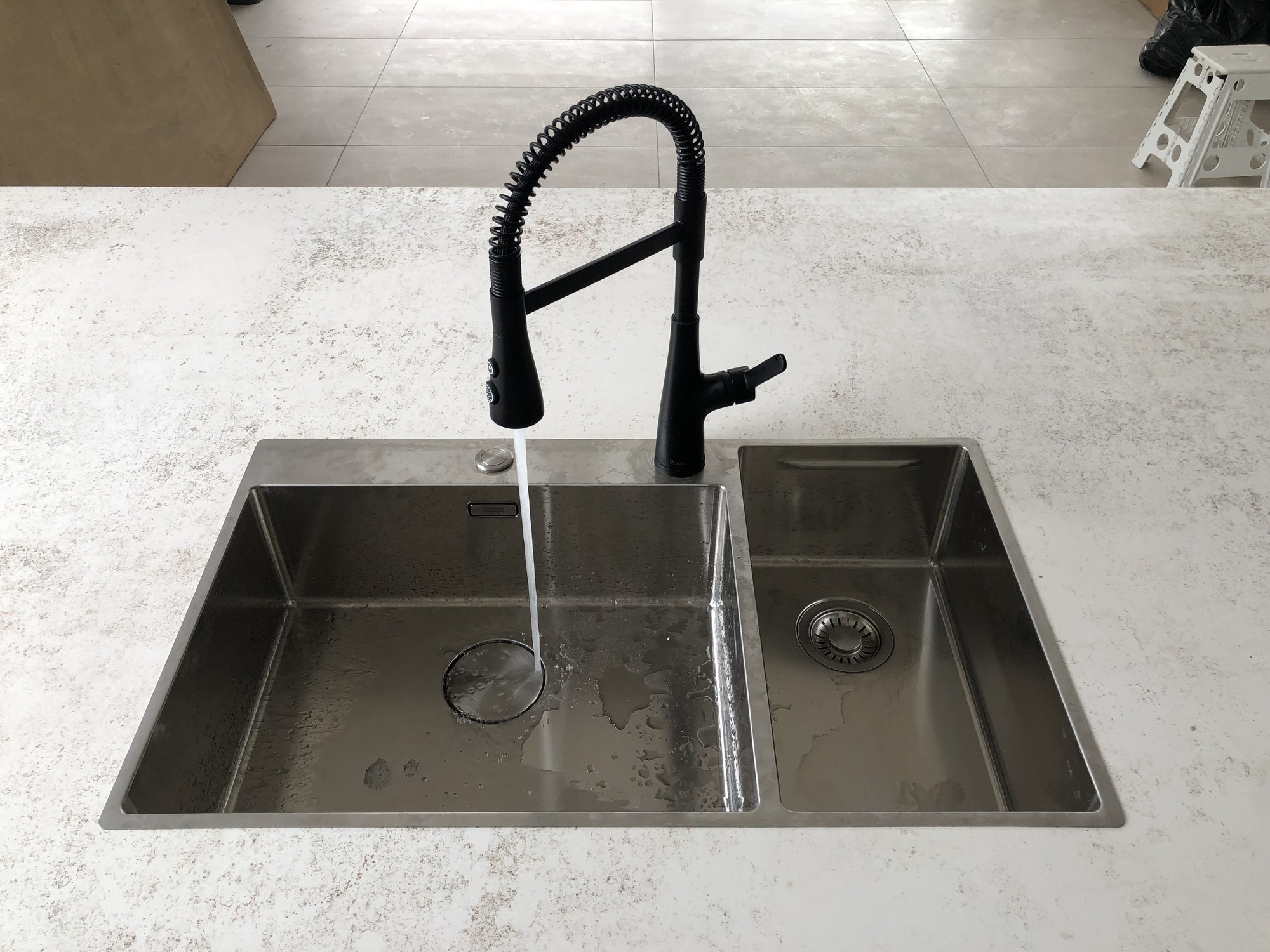 Detalle de lavaplatos en cocina moderna con grifería negra y superficie en piedra funcional